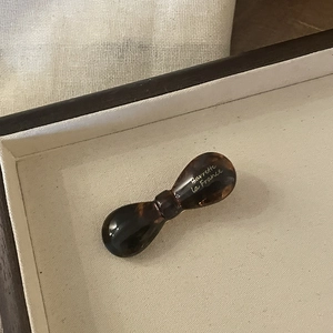 French tortoise shell acetate hair clip with golden logo in a luxury display tray