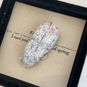 Gros plan d'une pince à cheveux en tricot français avec fils colorés et détails de tissu