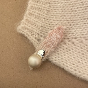 Detail of knitted hair clip featuring pink ribbon, silver Princess charm, and white pearl