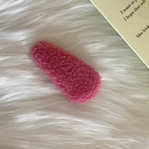 Detail of soft dark pink plush lamb wool teardrop hair clip on a fluffy white background