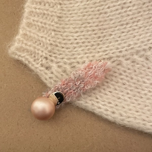 Detail of pink knitted butterfly hair clip featuring a large champagne pearl and gold clasp