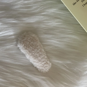 Close-up of a white plush lamb wool hair clip featuring a soft faux fur texture on the surface