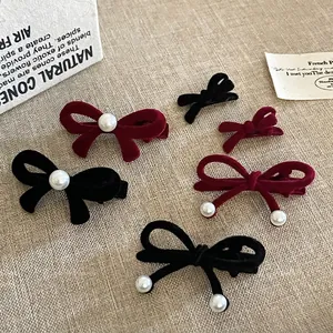 Set of velvet bow hair clips in black and wine red with pearls on linen background