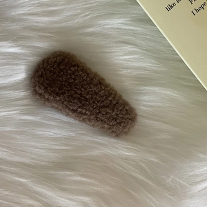 Detailed macro view of the soft coffee brown teddy plush texture on a warm winter hair clip