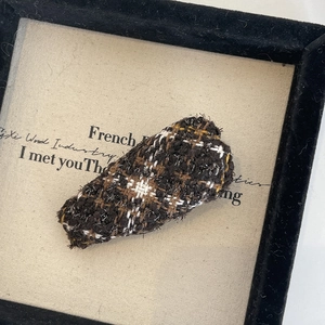 Vue macro d'une pince à cheveux en tweed français avec motif à carreaux marron et blanc