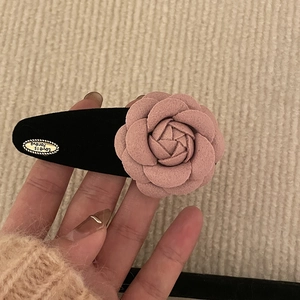 Pince à cheveux fleur de camélia rose avec base en velours et étiquette dorée