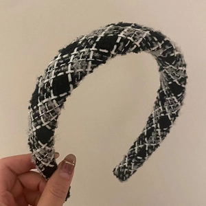 Détail d'un serre-tête en tweed noir et blanc avec tissage de fils métalliques argentés