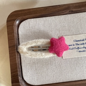 Handmade knitted hair clip with pink star on wooden tray for women's hair styling