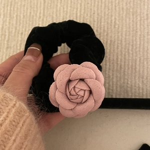 Détail d'un chouchou en velours rose avec camélia et texture douce au design floral