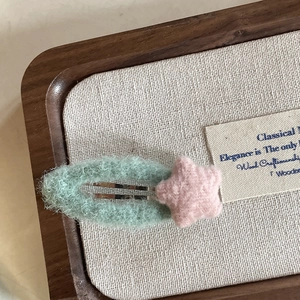Sweet mint green plush heart hair clip with pink star on a textured display tray