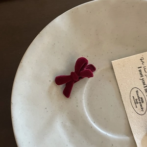Detailed view of the vintage wine red velvet bow hair clip on a white ceramic plate