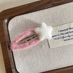 Close-up of pink felt star hair clip with handmade wool texture on a linen background