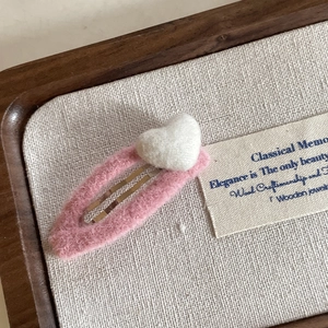 Close-up of pink plush heart hair clip with white 3D heart on a BB snap fastener