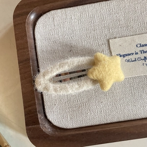 Close-up of cute cream plush star hair clip on a minimalist wooden tray display