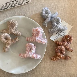 Pinces à cheveux en laine tricotée grise, rose et marron sur une assiette décorative