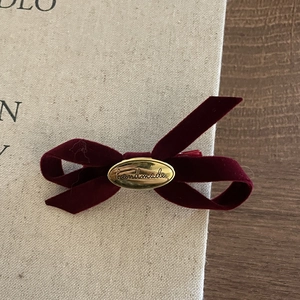 Exquisite burgundy velvet bow hair clip with gold handmade metal plaque on a textured book