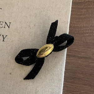 Detailed macro view of black sparkling bow hair clip with golden handmade metal emblem
