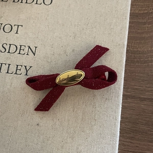 Detail of red velvet bow hair clip featuring a gold metal piece with handmade engraving