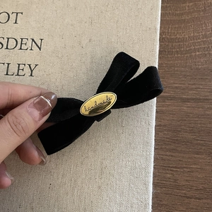 Close-up of black velvet bow hair clip featuring a gold handmade metal plate