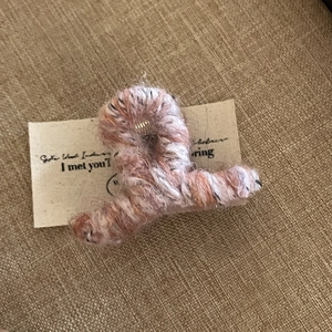 Détail d'une pince à cheveux en laine avec texture tricotée chinée marron et ressort métal
