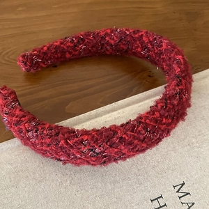 Red tweed knotted headband with silver glitter thread for women on a wooden desk