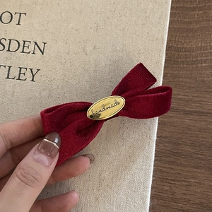 Macro detail of red velvet bow hair clip with golden handmade metal buckle texture