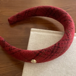 Close-up of red and black plaid tweed headband with vintage gold metal logo button