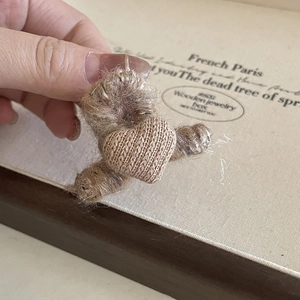 Detailopname van een pluche haarklem met een klein gebreid hartje op een lichte achterkant