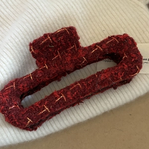 Macro detail of red tweed fabric shark hair claw clip with golden thread stitching