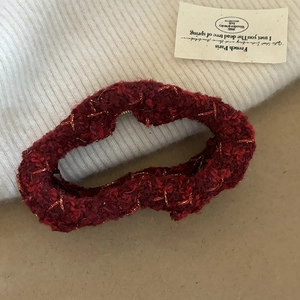 Detail of red tweed hair claw clip with golden thread accents for festive styling