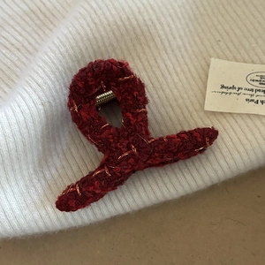 Close-up of a burgundy tweed shark hair claw clip with elegant gold thread details