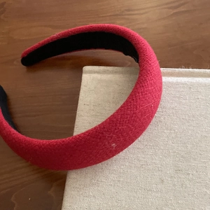 Close-up of thick red velvet padded headband texture on books and wooden desk