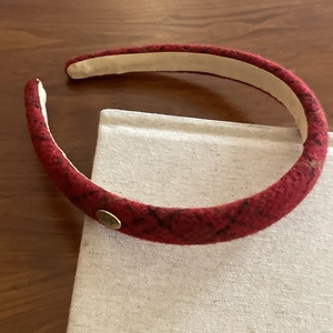 Detail of red tweed headband with golden metal logo on textured fabric book