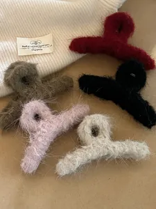 Dettaglio di cinque mollette per capelli in peluche in vari colori per lo stile invernale