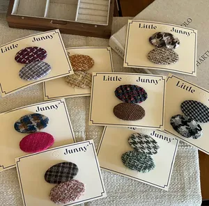 Detailed view of oval tweed hair clips in various colors on beige card holders
