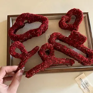 Set of four red tweed hair claw clips with gold tinsel detail on a wooden tray