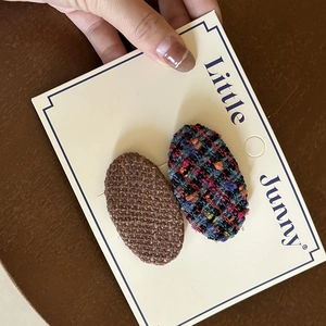 Detail of tweed and woven oval hair clips in brown and colorful patterns on a card