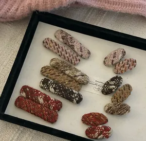 Close-up of assorted tweed woven BB hair clips in various colors on a display tray
