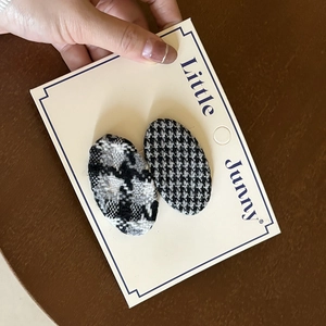Detail of two French style oval hair clips with classic houndstooth and checkered patterns