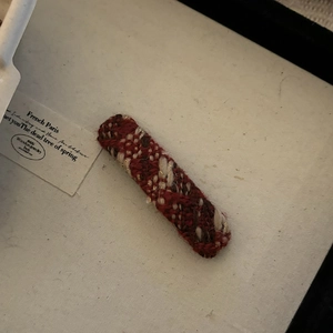 Detailed view of large plaid knitted hair clip with vintage red and brown yarn patterns