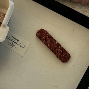 Detail of red and brown tweed fabric hair clip with elegant French vintage style texture