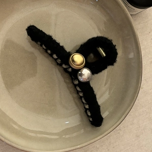 Gros plan détaillé d'une pince à cheveux en tricot noir avec boutons métalliques