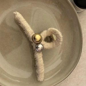 Détail d'une pince à cheveux en laine tressée avec perles dorées et argentées