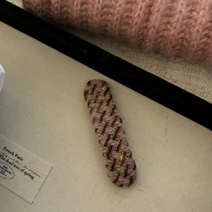 Detailed macro view of a vintage hand-knitted plaid hair clip in pink brown texture