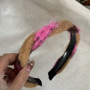 Détail d'un serre-tête tressé en peluche marron et rose sur une texture en toile de lin