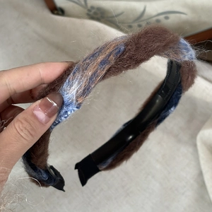 Détail d'un serre-tête tressé en peluche marron et bleu-gris à texture douce