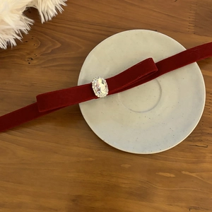 Close-up of a deep red velvet bow hairpin with a central oval crystal and rhinestone trim