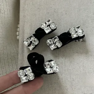 Dettaglio del fermaglio a fiocco in velluto nero con strass di cristallo brillanti