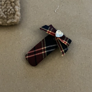Detail einer karierten Haarschleife mit herzförmigem Strassstein und britischem Preppy-Stil