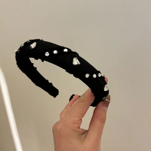 Detail of black fabric headband with sparkling round and heart-shaped rhinestones